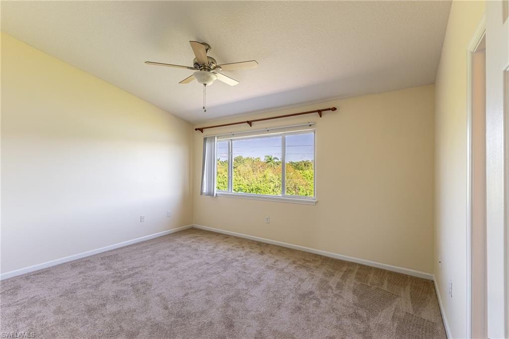 Carpeted spare room featuring lofted ceiling and ceiling fan