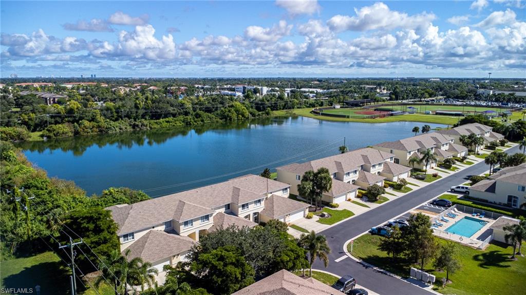 Aerial view of residential area with a large body of water and a tree filled landscape