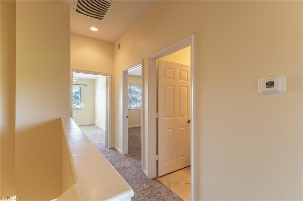 Hall with an upstairs landing, light carpet, and light tile patterned floors
