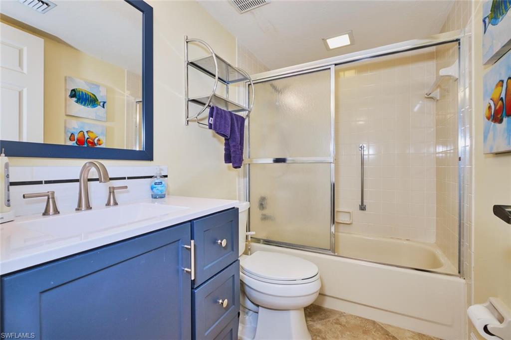 Full bathroom with combined bath / shower with glass door, vanity, and light tile patterned flooring