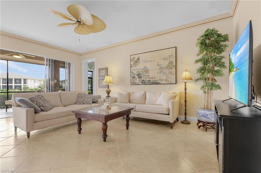 Living area featuring light tile patterned floors, ornamental molding, and a ceiling fan