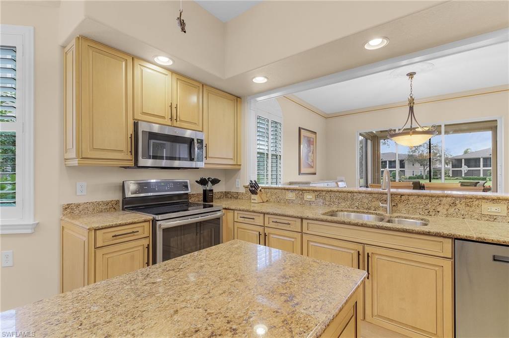 Kitchen featuring stainless steel appliances, recessed lighting, decorative light fixtures, light brown cabinets, and light stone counters