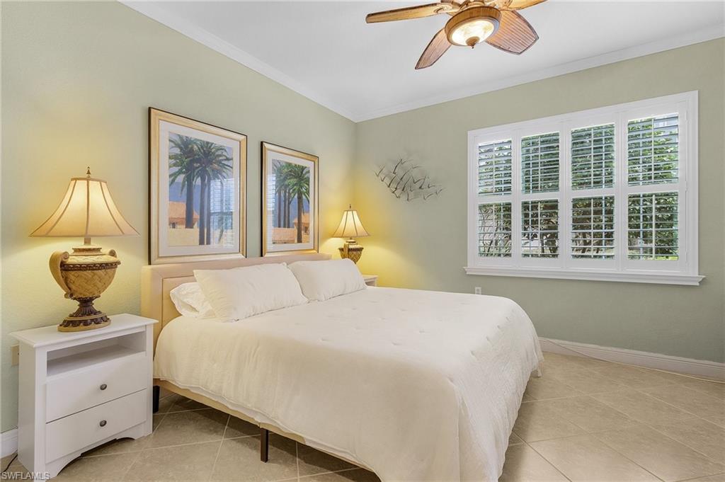 Bedroom with crown molding, light tile patterned floors, and a ceiling fan