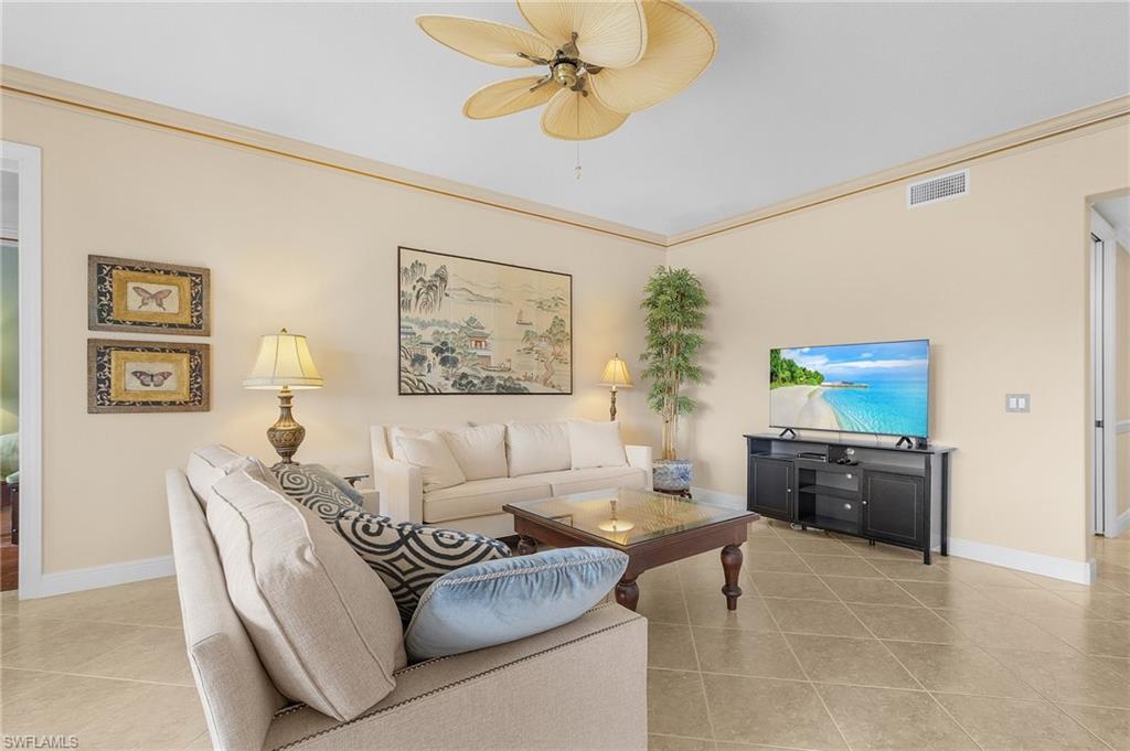 Living room featuring ornamental molding, light tile patterned floors, and ceiling fan