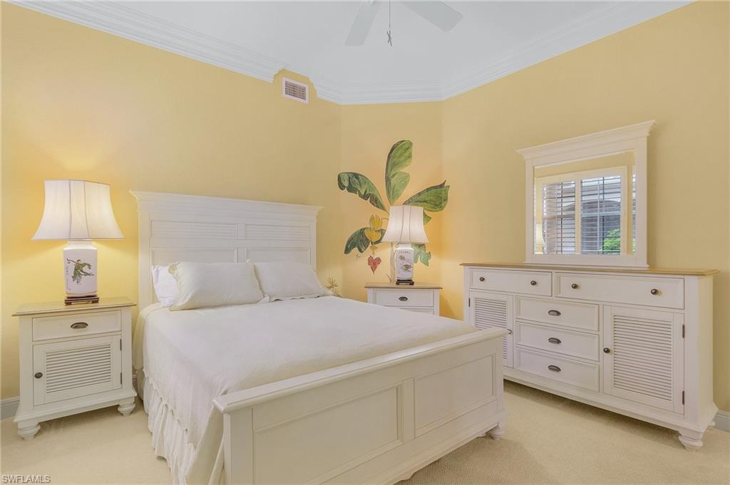 Bedroom with light carpet, ornamental molding, and ceiling fan
