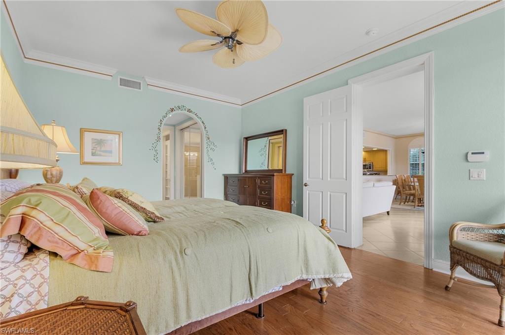Bedroom with crown molding, wood finished floors, and ceiling fan
