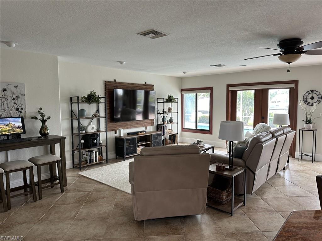 Living area featuring a textured ceiling, ceiling fan, and light tile patterned floors