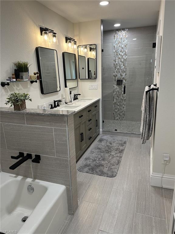 Bathroom with a stall shower, a garden tub, double vanity, and recessed lighting
