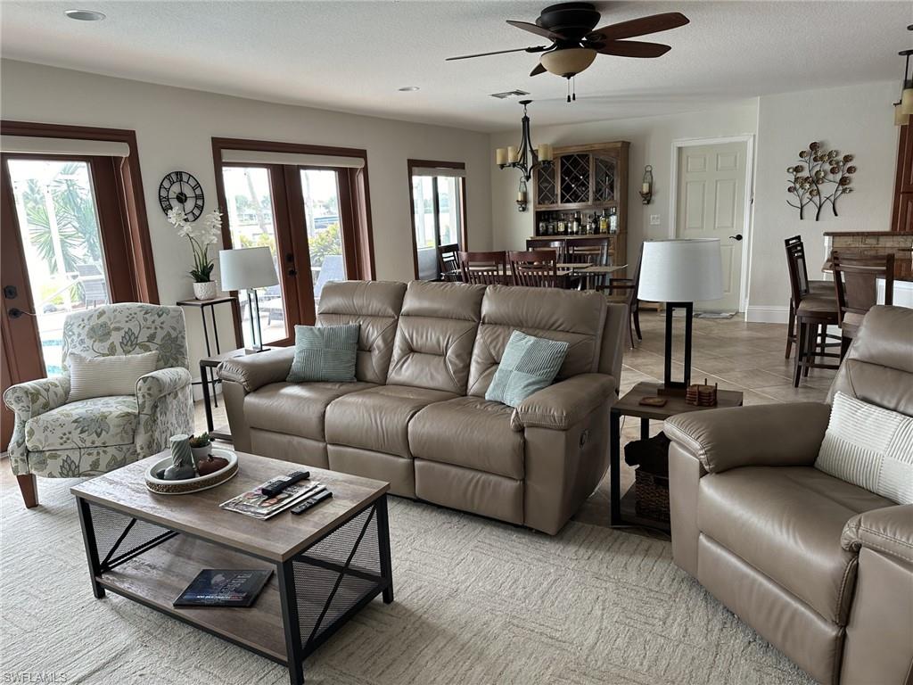 Living room with french doors, ceiling fan, a textured ceiling, and tile patterned floors