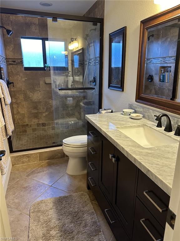 Full bathroom with vanity, a textured wall, a stall shower, and dark tile patterned flooring