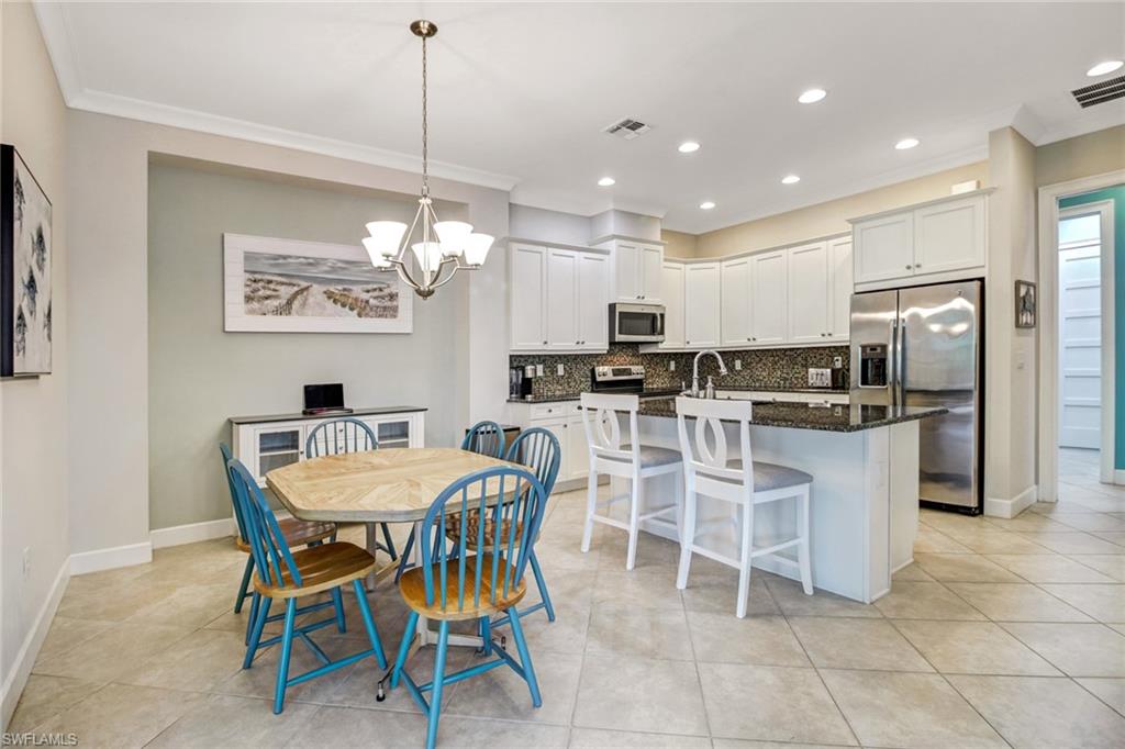 Dining space with ornamental molding, a chandelier, and light tile patterned floors