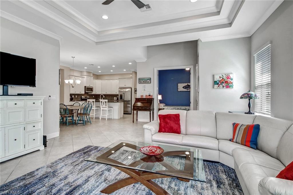 Tiled living room with crown molding and ceiling fan with notable chandelier
