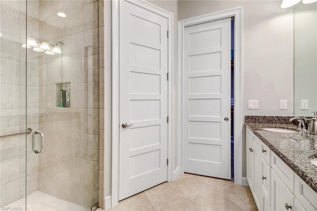 Bathroom featuring walk in shower, vanity, and tile patterned floors