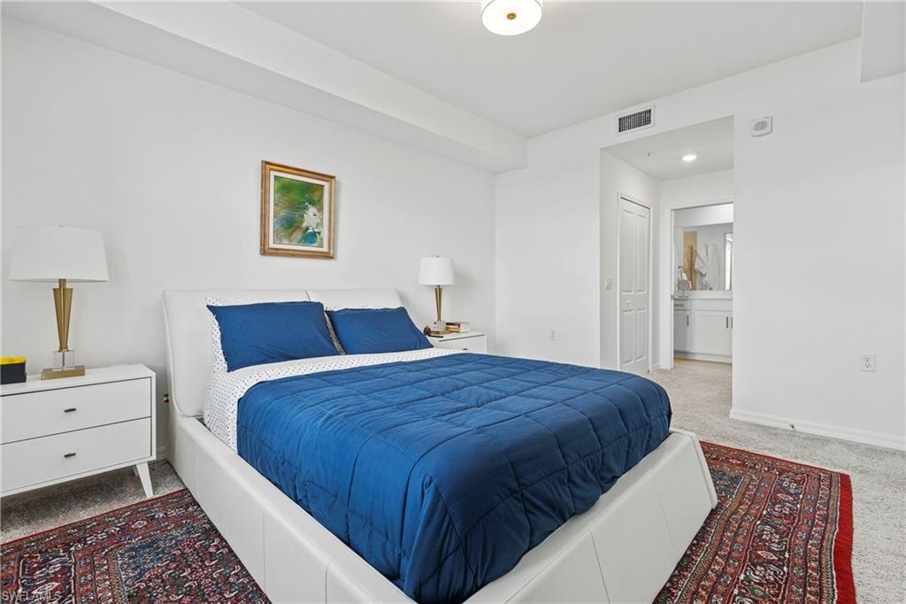 Carpeted bedroom featuring ensuite bathroom and baseboards