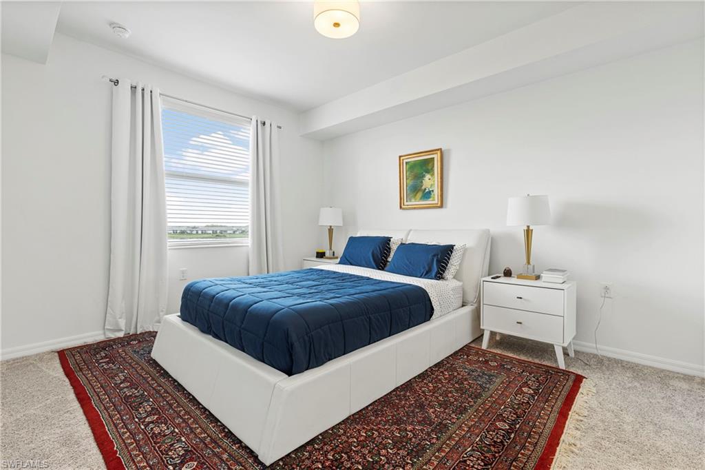 Bedroom featuring light carpet and baseboards
