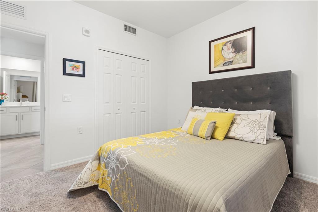 Bedroom with light colored carpet, a closet, and light tile patterned flooring