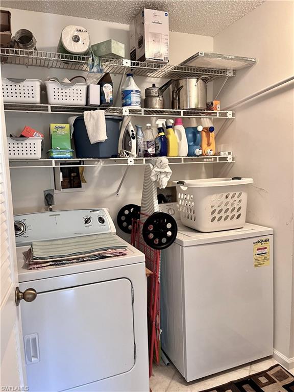 Laundry room with a textured ceiling and washing machine and dryer and walk-in closet area for storage