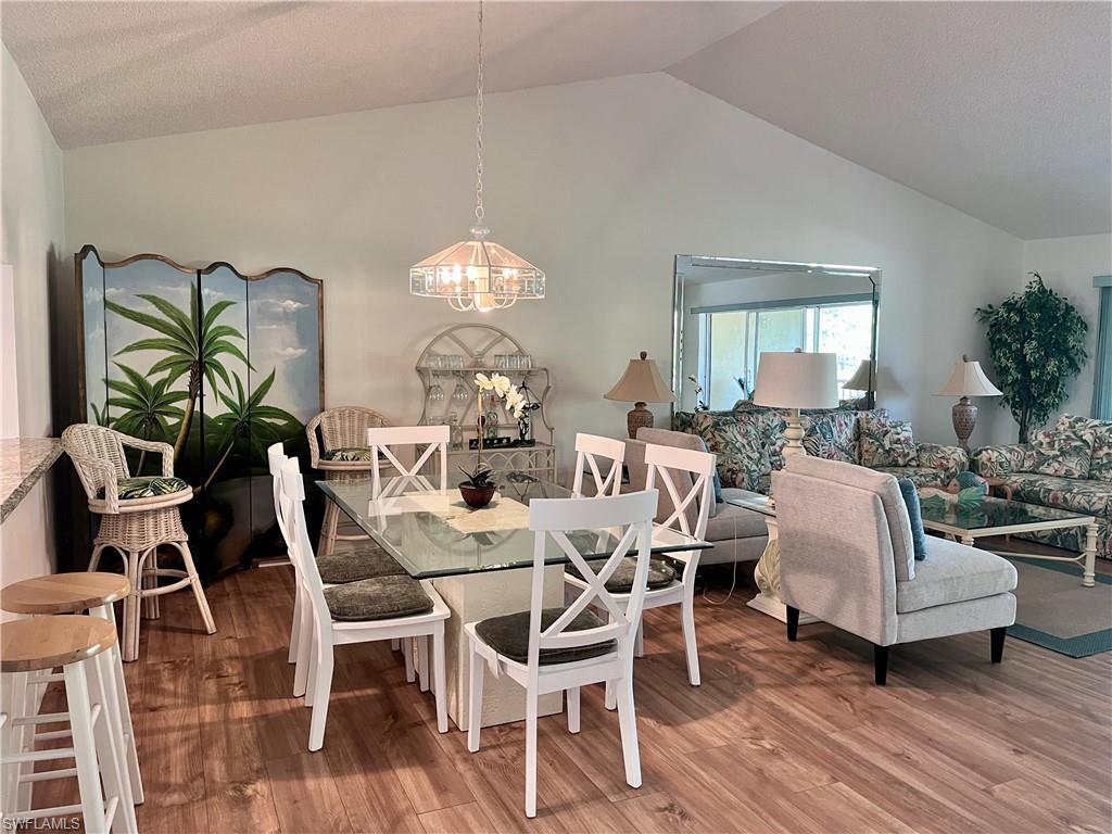 Dining room with lofted ceiling, a chandelier, and wood-style laminate floors