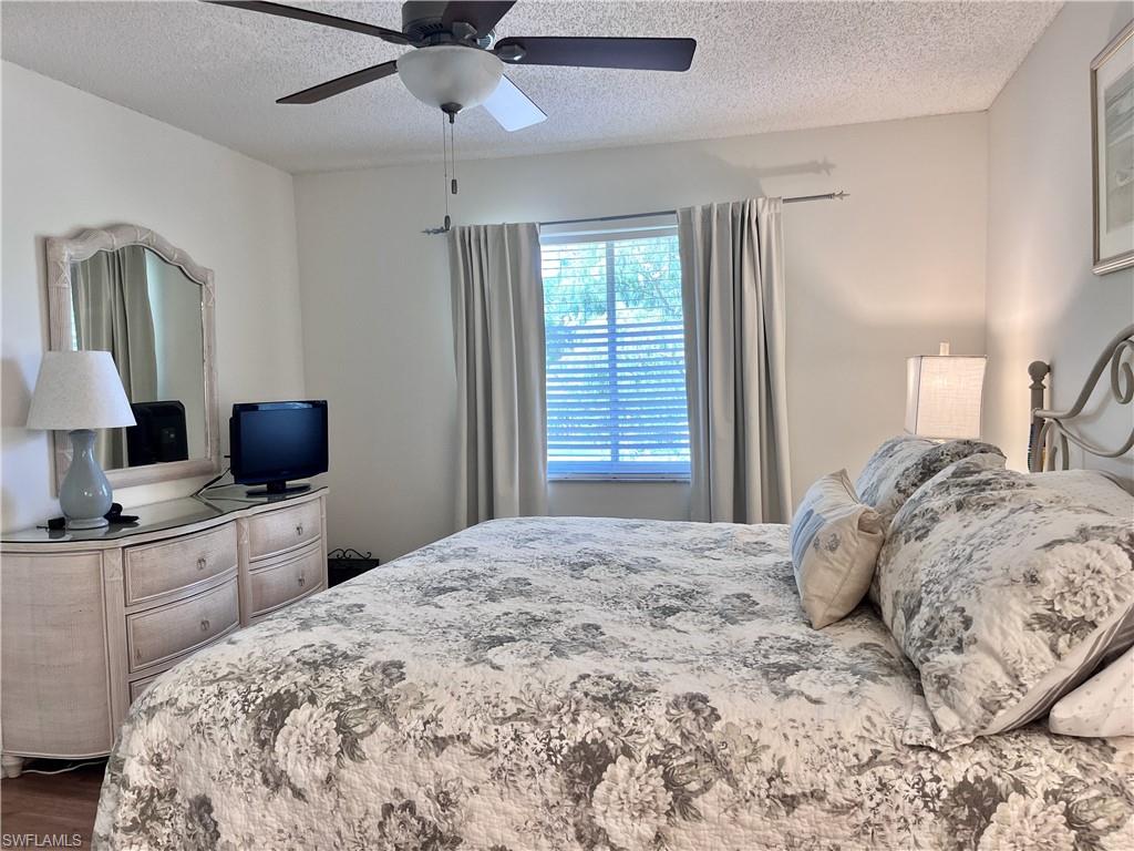 Bedroom featuring ceiling fan, a textured ceiling, and dark wood-type flooring