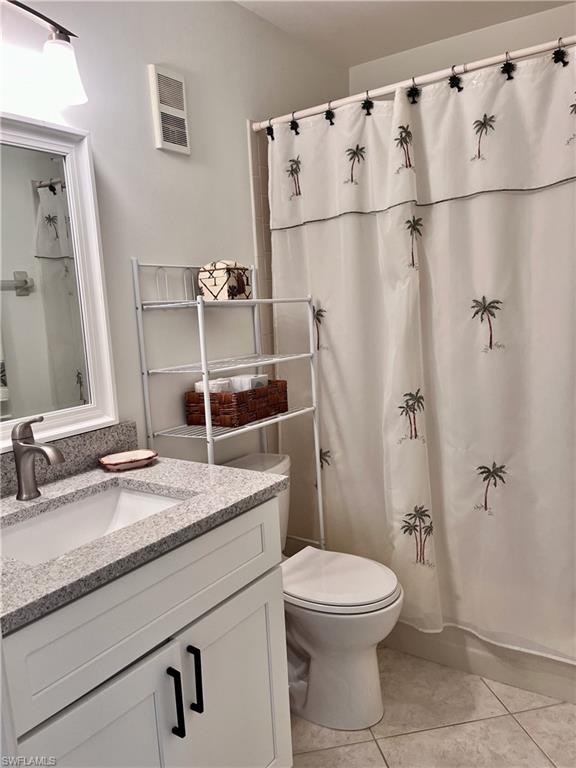 Bathroom with tile flooring, a shower with curtain, vanity, and toilet
