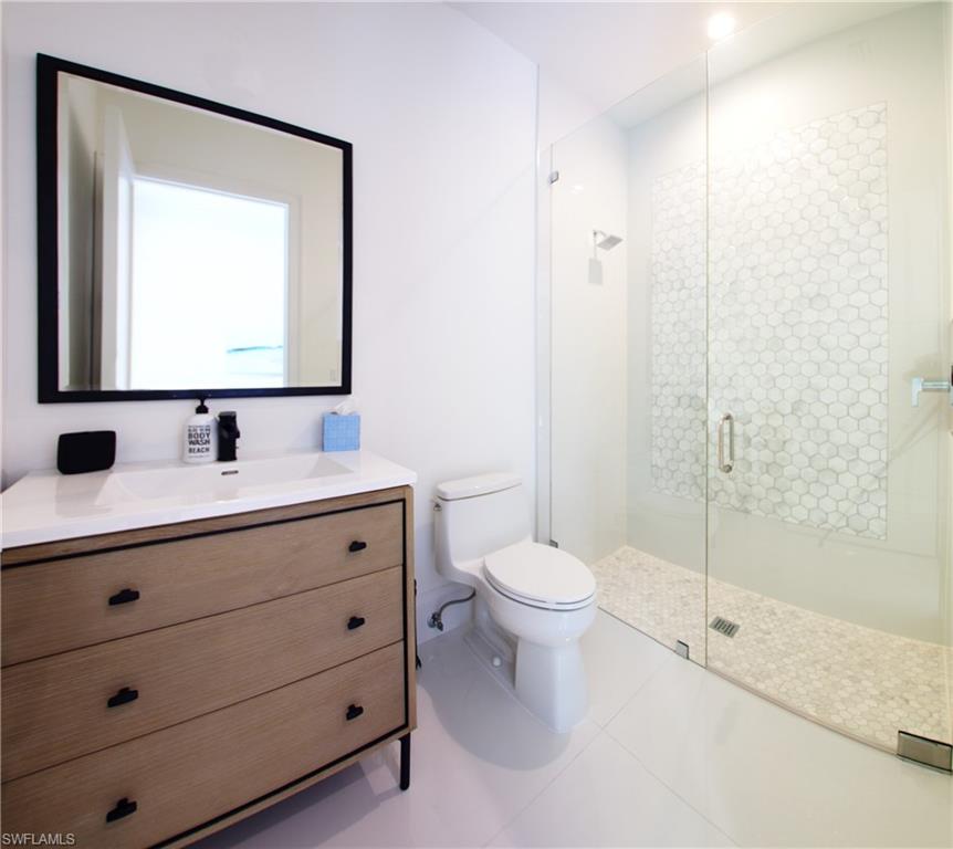 Bathroom with tile patterned flooring, a shower with shower door, toilet, and vanity