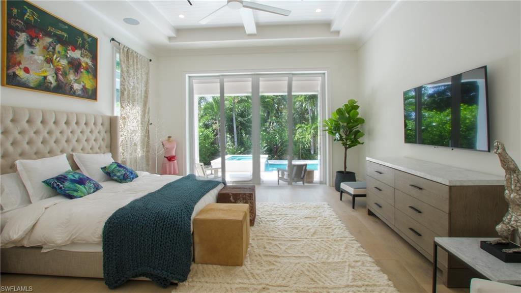 Bedroom featuring access to exterior, ceiling fan, light wood-type flooring, and a tray ceiling