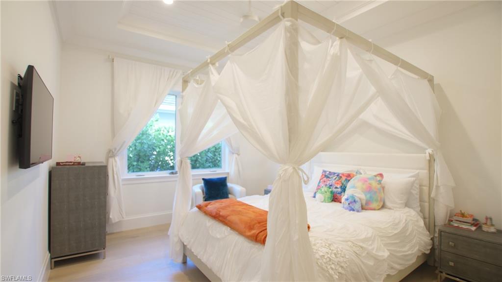 Bedroom with a raised ceiling and light hardwood / wood-style flooring