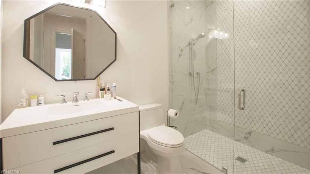 Bathroom featuring a shower with shower door, toilet, and vanity