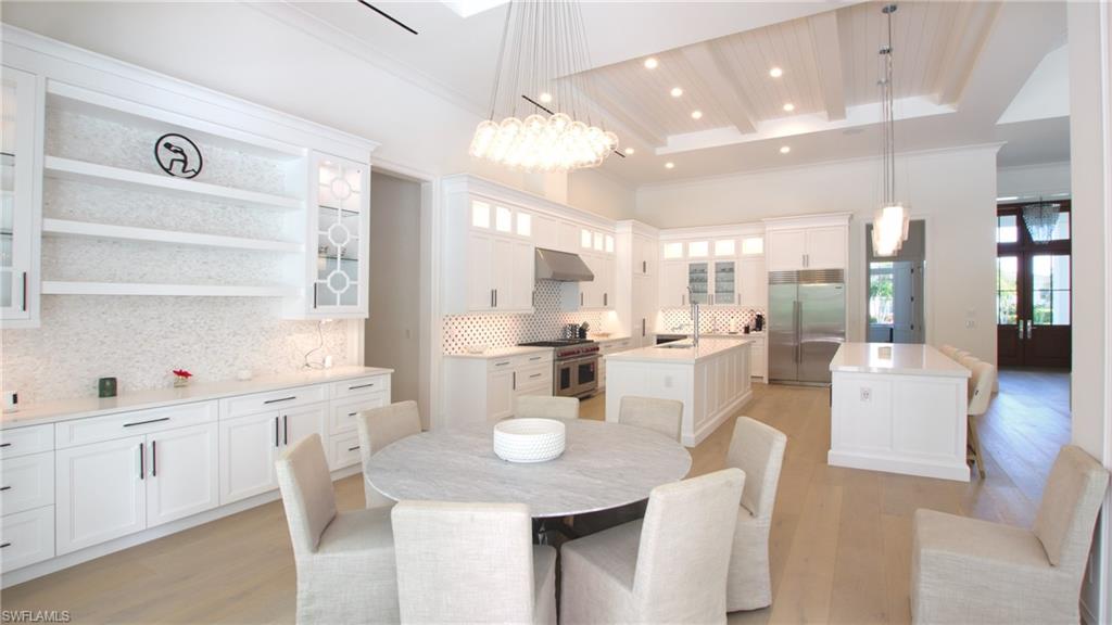 Dining area with a raised ceiling, sink, a notable chandelier, and light wood-type flooring