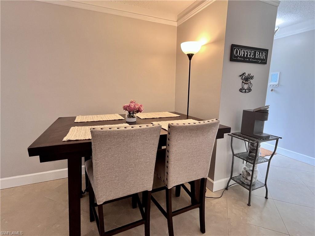 Dining space featuring a textured ceiling, crown molding, coffee bar and light tile flooring