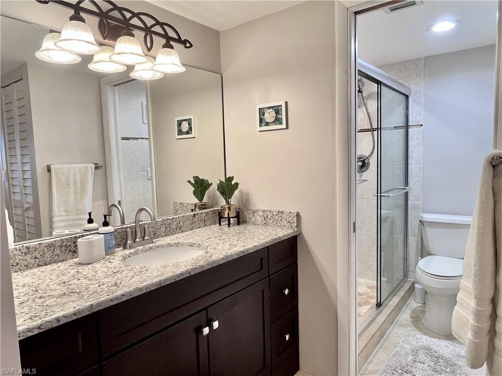 Full bathroom with vanity, a shower stall, and light tile floors