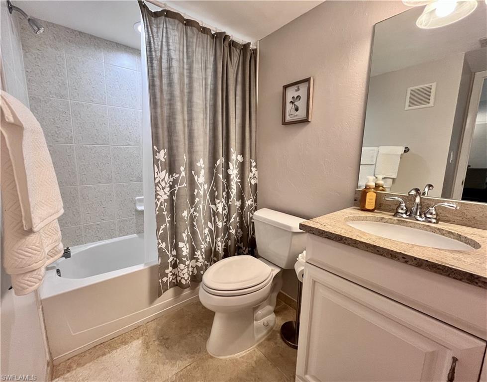 Bathroom with shower / bath combo, vanity, a textured wall, and light tile floors