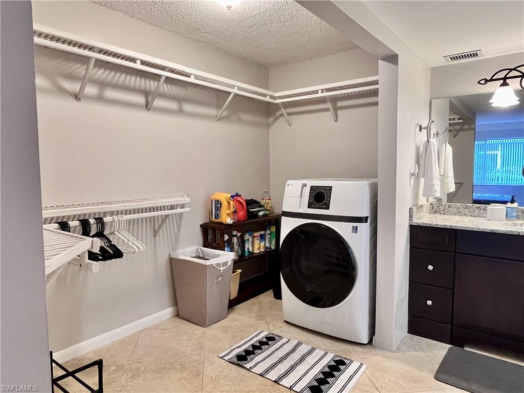 Large walk in closet with an abundance of storage space, including the laundry featuring a washer/dryer combination unit with light tile floors.