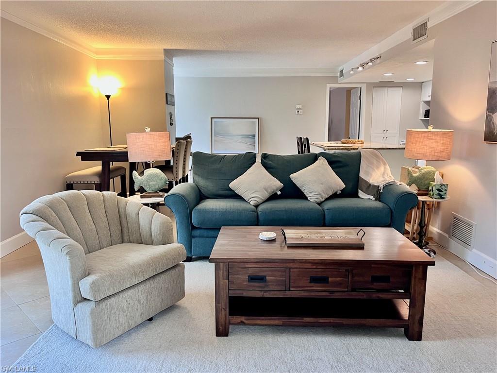 Living area with ornamental molding, a textured ceiling, and tile flooring