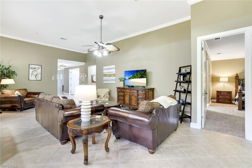Living room featuring ornamental molding, light tile patterned floors, and a ceiling fan