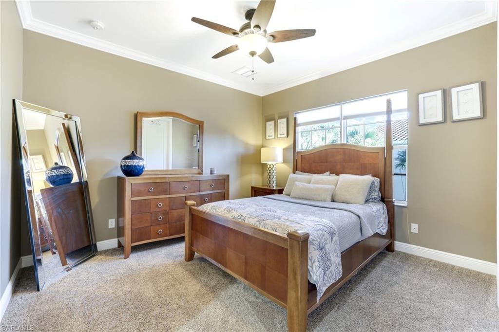 Bedroom featuring ornamental molding, light carpet, and a ceiling fan