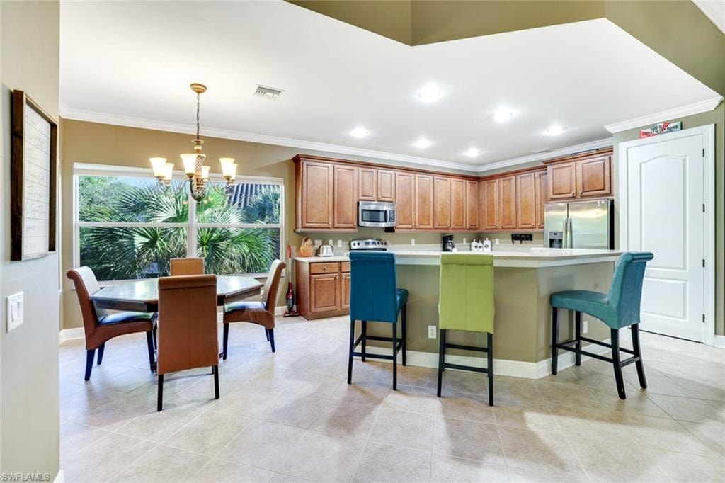 Kitchen featuring a kitchen bar, crown molding, a center island, light countertops, and appliances with stainless steel finishes