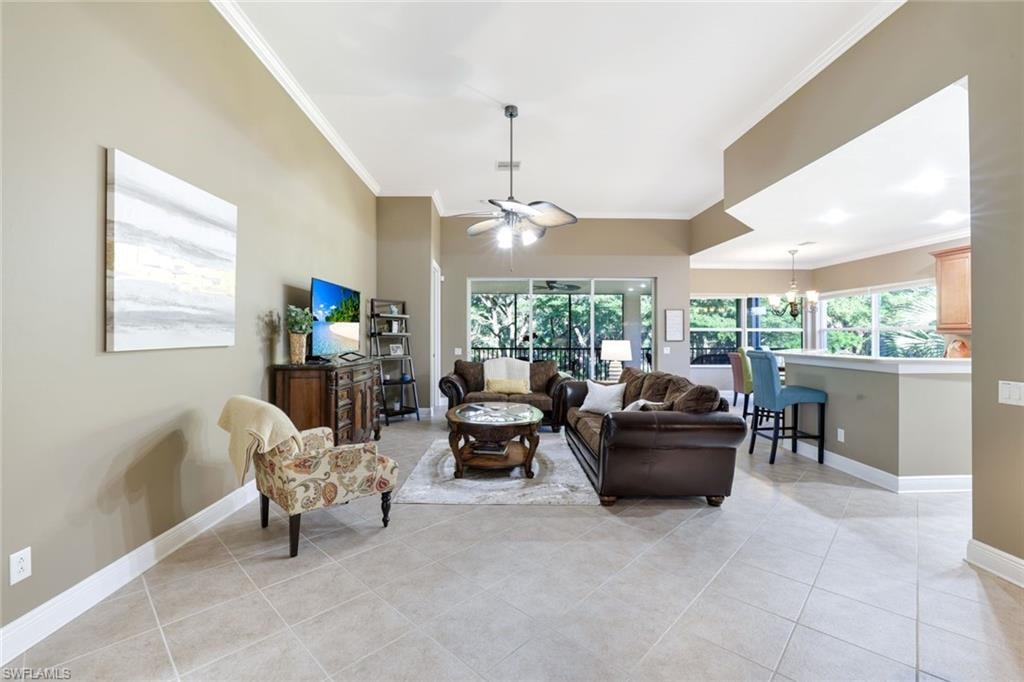 Living area with crown molding, light tile patterned floors, a chandelier, and a ceiling fan