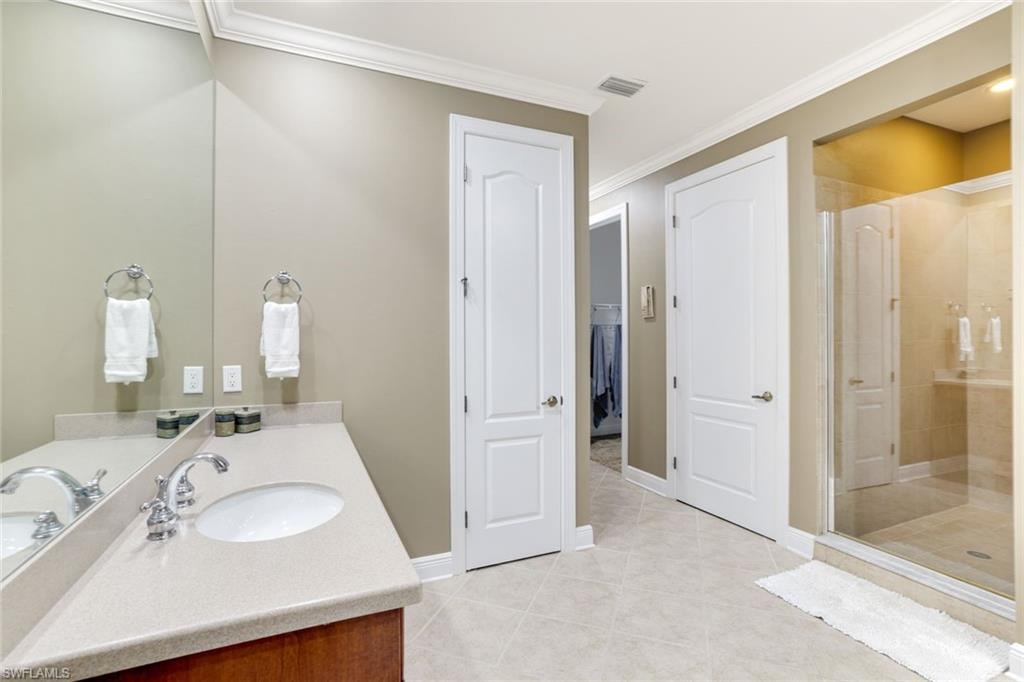 Bathroom with a stall shower, light tile patterned flooring, ornamental molding, vanity, and a closet