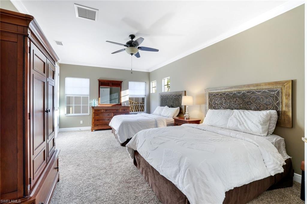 Bedroom featuring light carpet, ornamental molding, and a ceiling fan