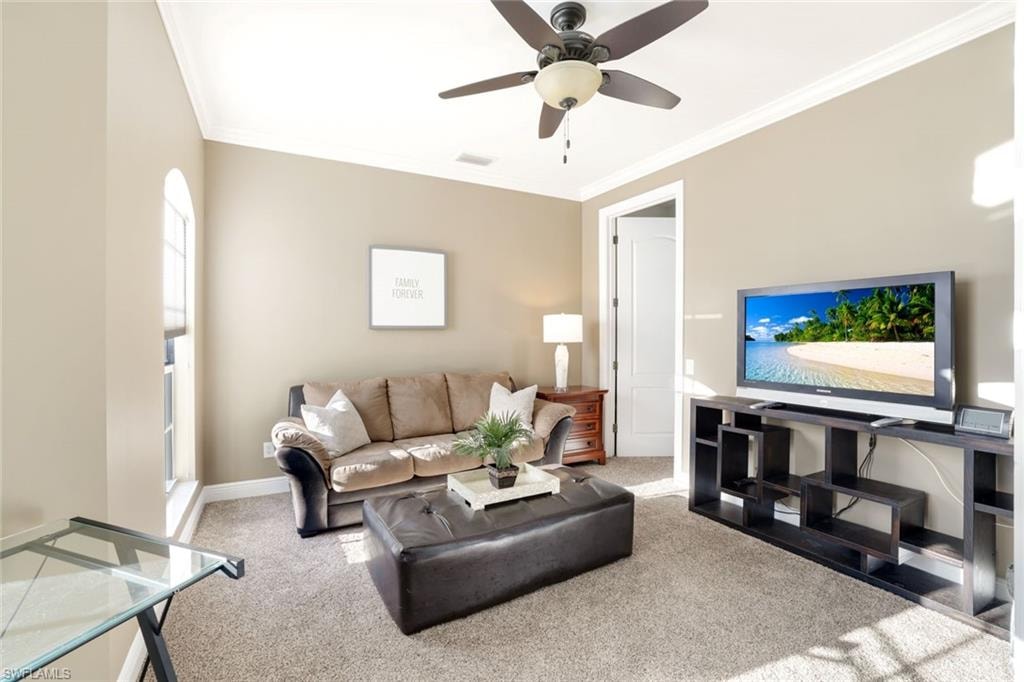 Living area with ornamental molding, light colored carpet, and a ceiling fan