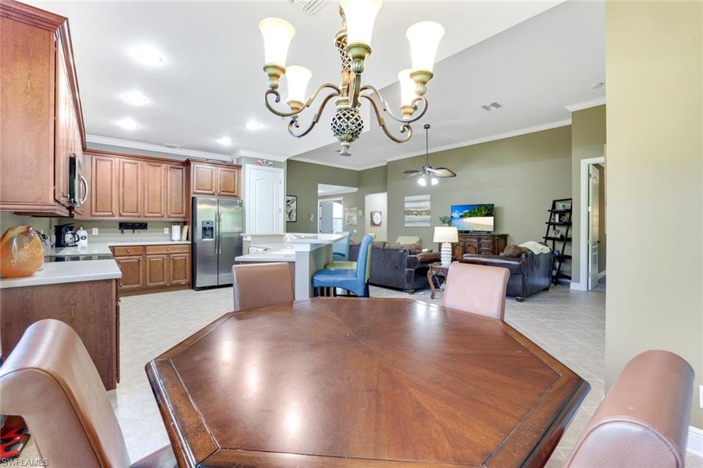 Dining area featuring crown molding, a chandelier, a ceiling fan, and recessed lighting