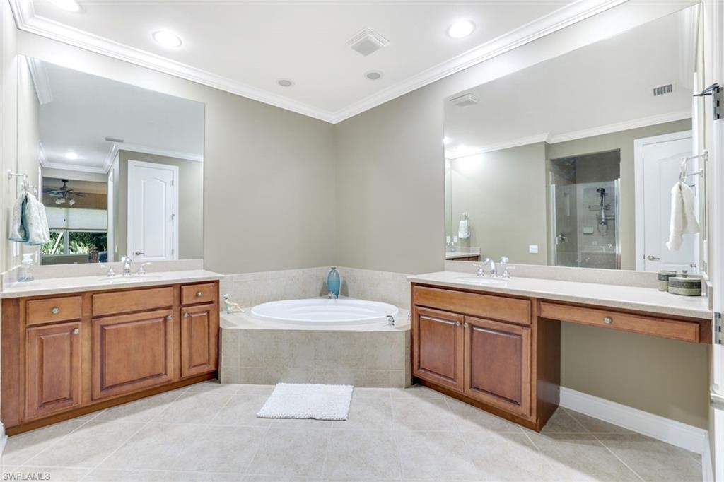 Full bathroom with light tile patterned floors, a stall shower, two vanities, a garden tub, and crown molding