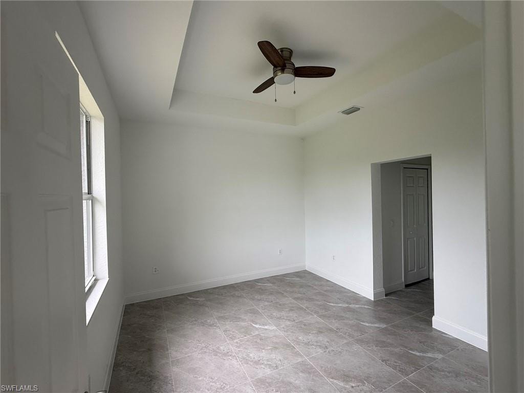 Empty room with a raised ceiling and ceiling fan