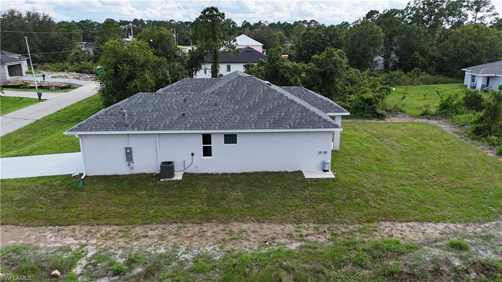 View of property exterior with a lawn, stucco siding, and a shingled roof