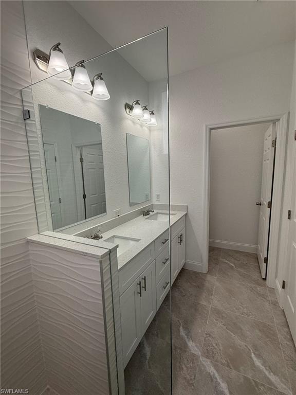 Bathroom with double vanity, walk in shower, and a textured wall