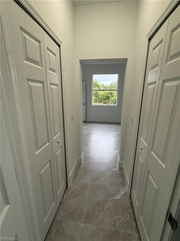 Hall featuring a textured wall and baseboards