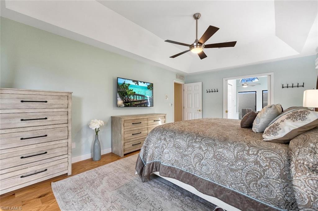 Bedroom with a tray ceiling, light wood-style floors, and a ceiling fan