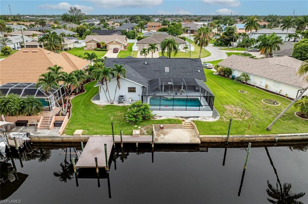 Aerial perspective of suburban area featuring a pool and a nearby body of water
