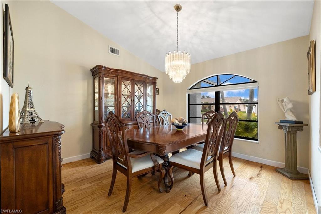Dining space with vaulted ceiling, light wood-style flooring, and a chandelier